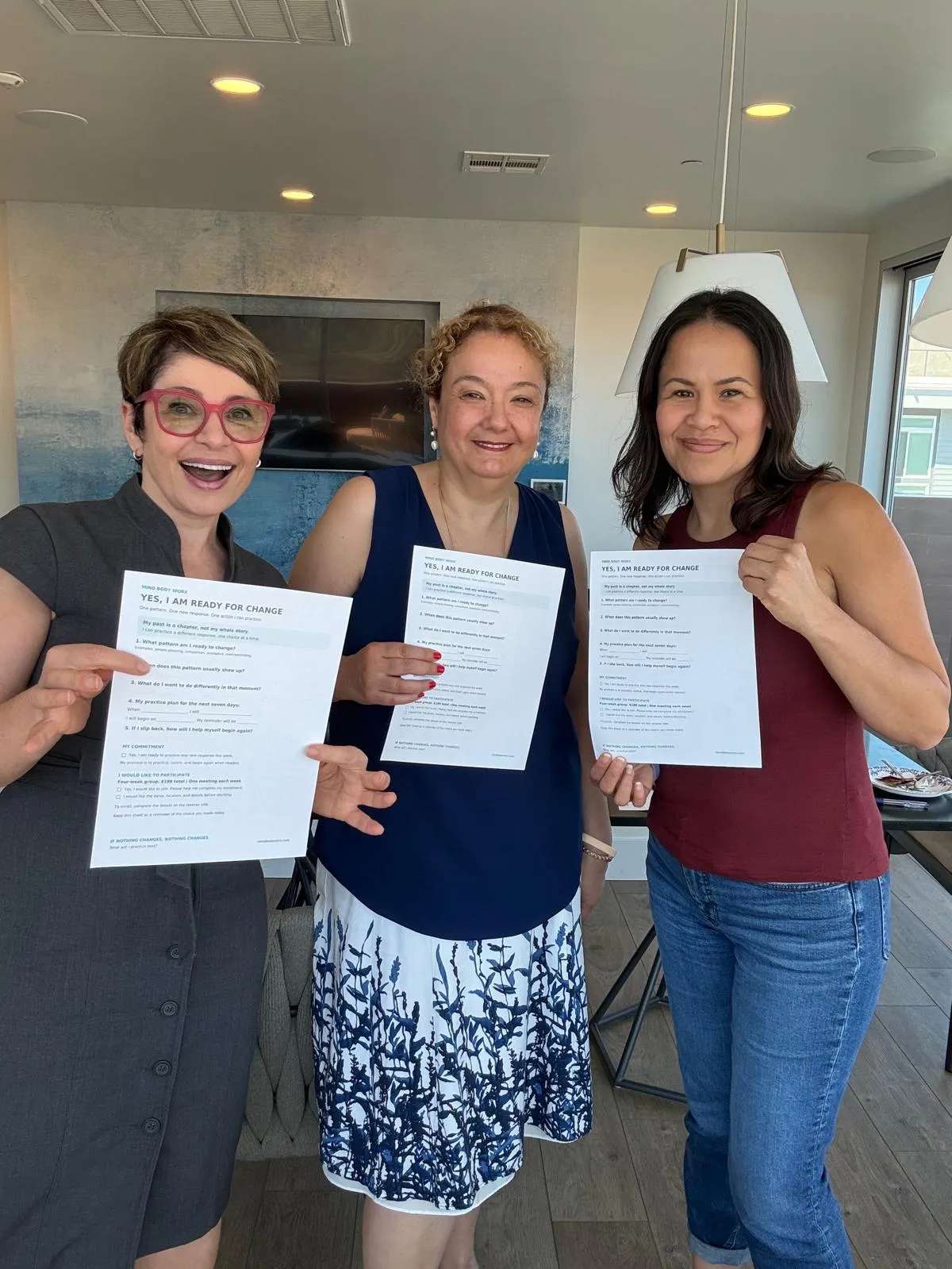 Mehri and two guests holding up their Yes, I Am Ready for Change worksheets