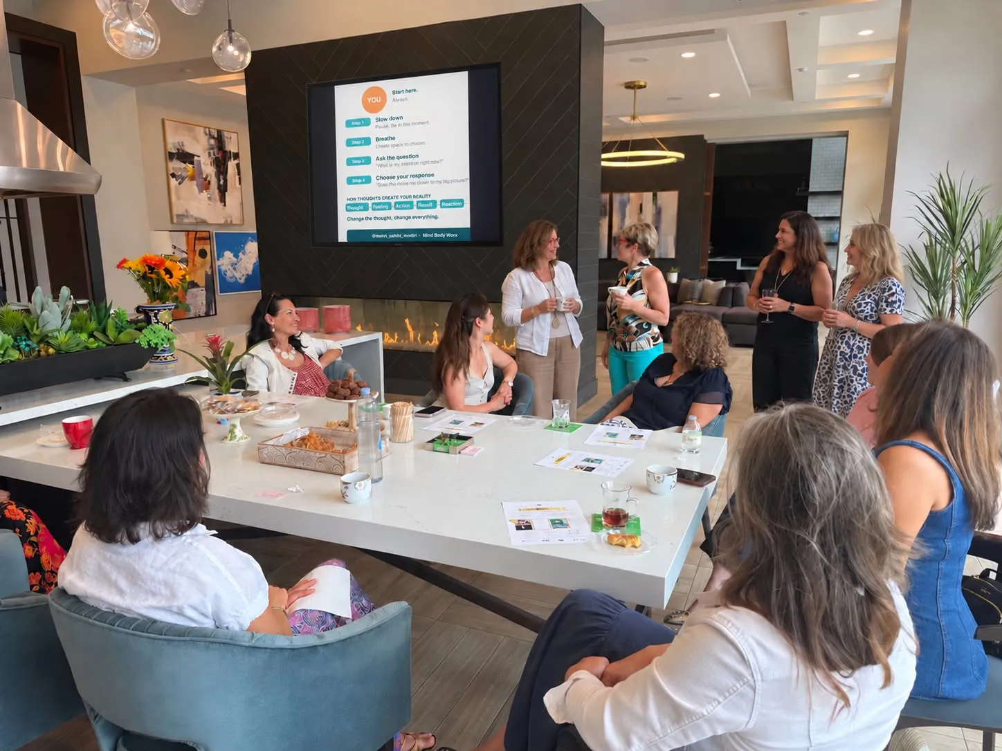 Women talking and smiling around a long table during a Mind Body Worx gathering