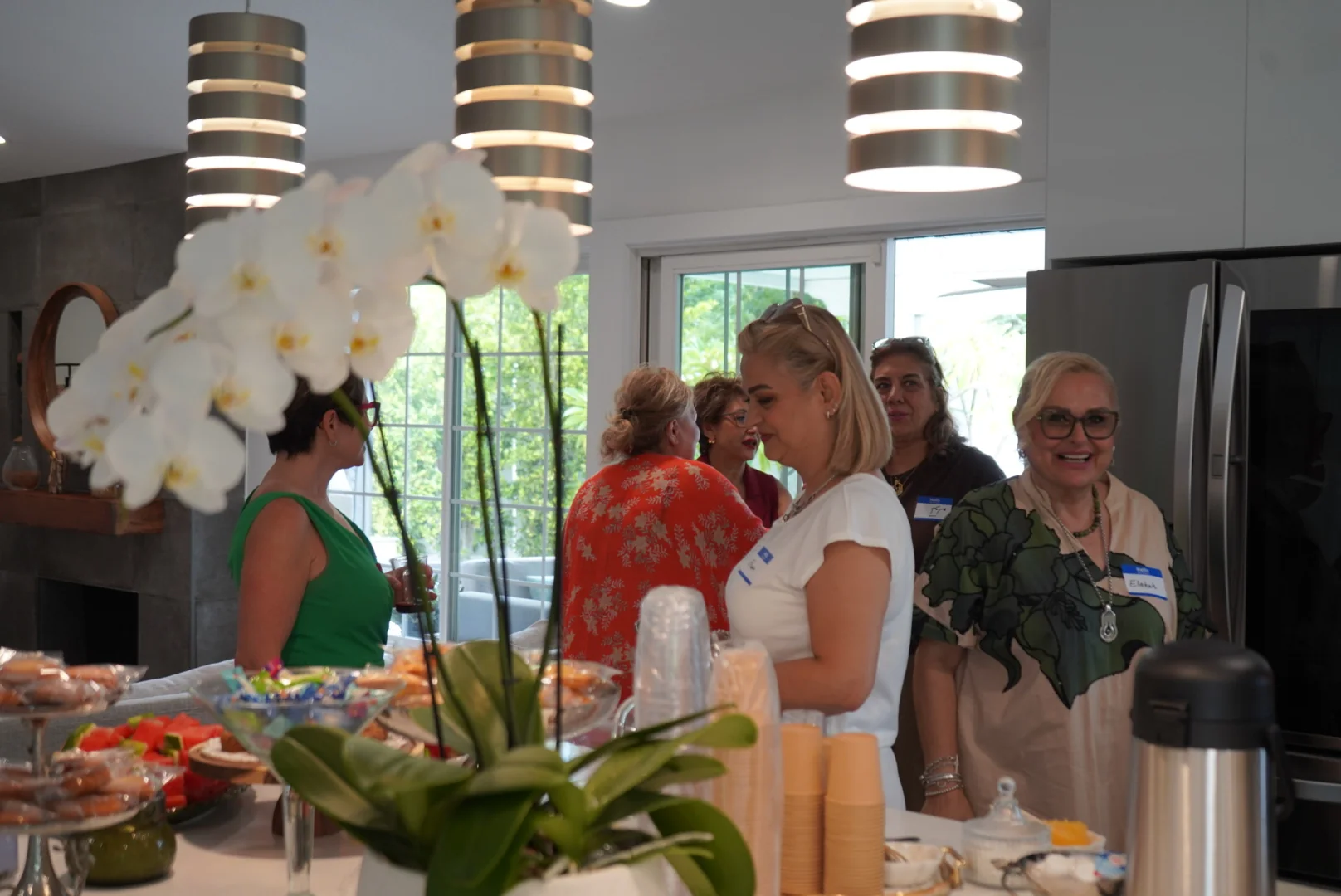 Guests chatting around the brunch table, seen across flowers and refreshments